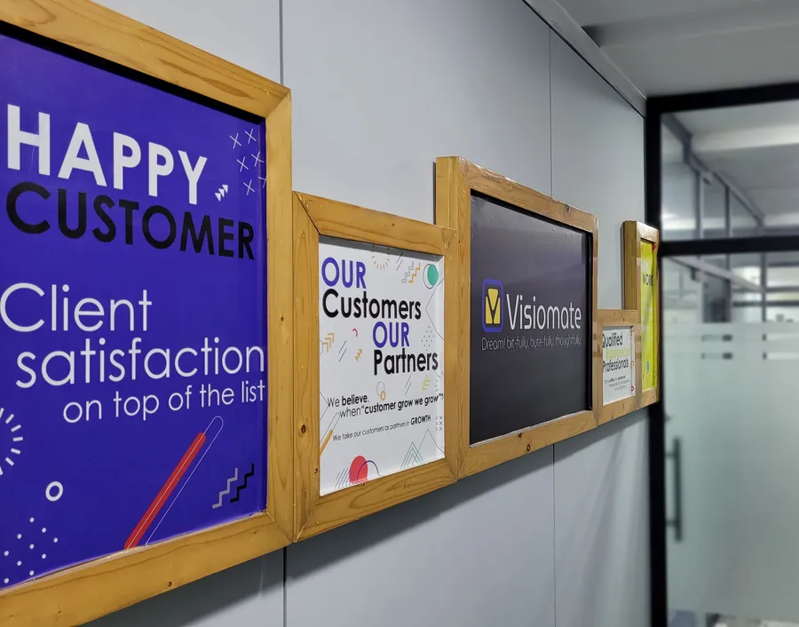 A wall inside the Visiomate office reading "Our Customers, Our Partners"